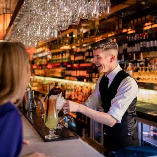 Bartender sonriente adorna cóctel en un elegante bar. 