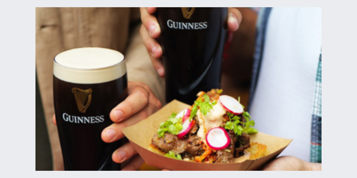 Dos vasos Guinness acompañado de comida que tiene carne y vegetales