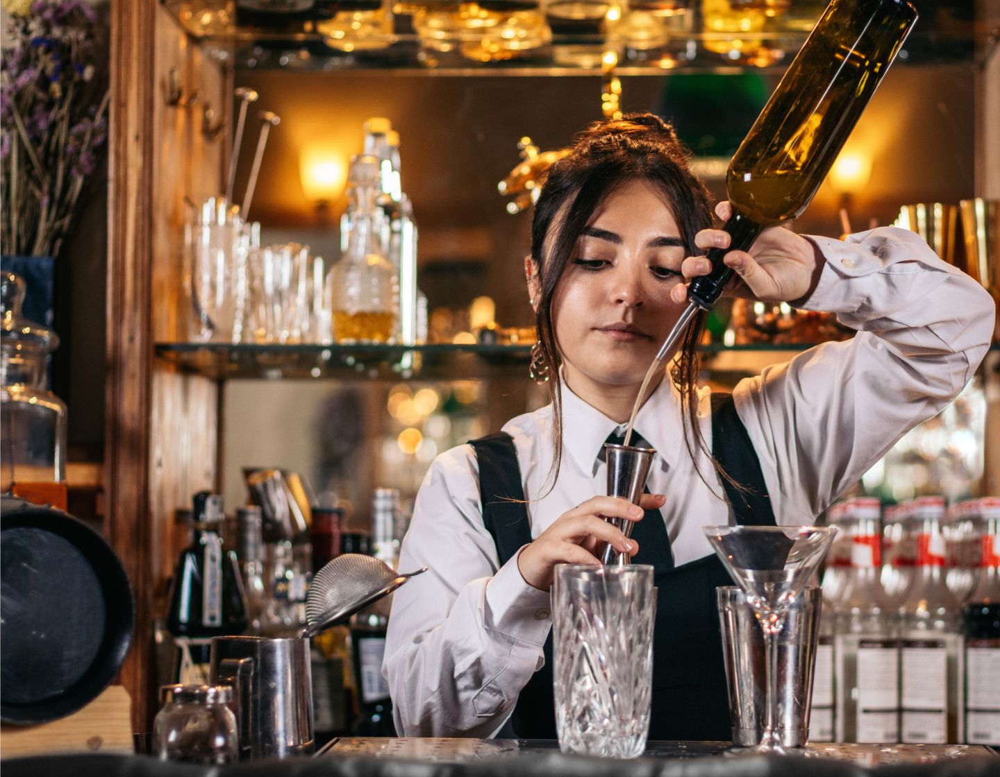 Bartender pouring from a bottle into a glass.