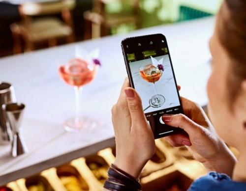 Bartender using iphone taking photo of cocktail