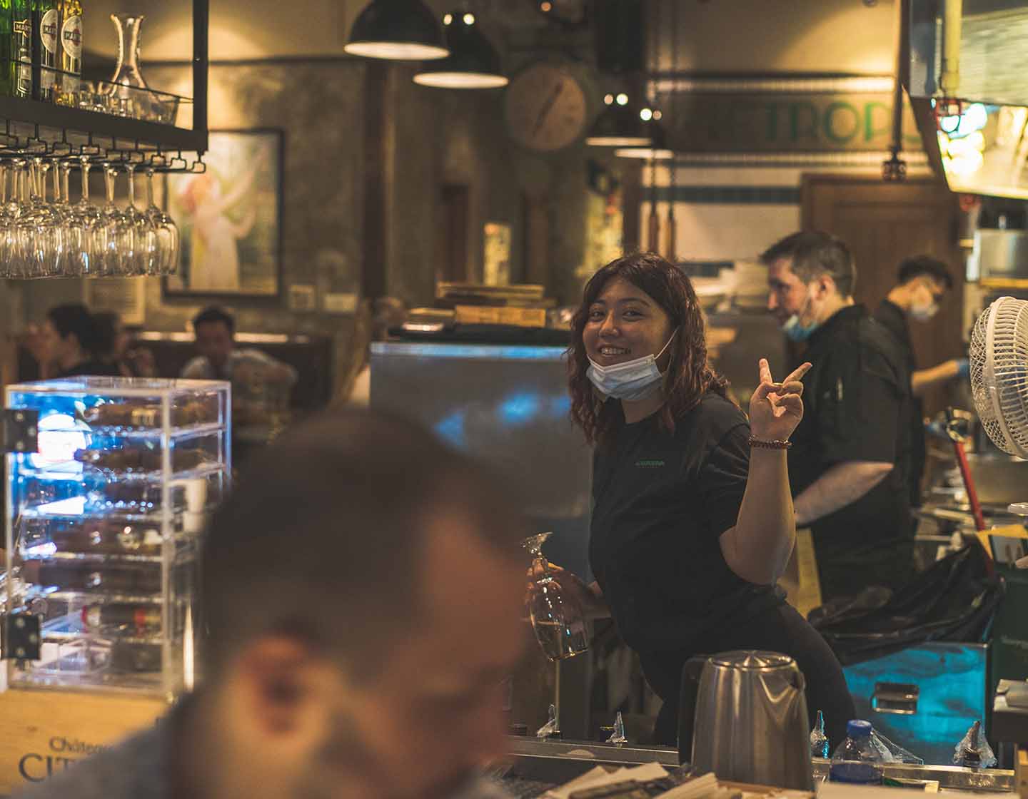 Bartender posing behind bar giving peace sign