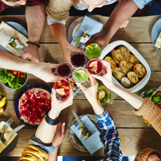 Personas brindan en la mesa con bebidas en la mano y platos pequeños en la mesa en un restaurante