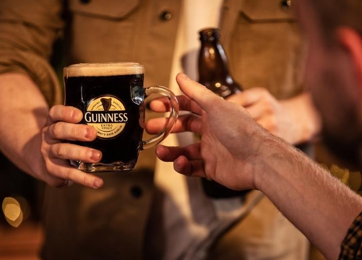 Hand reaching for a pint glass of Guinness Extra Stout