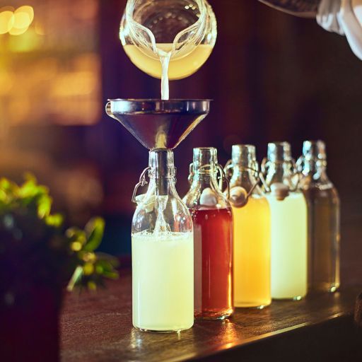 Batched cocktails being poured into bottles 