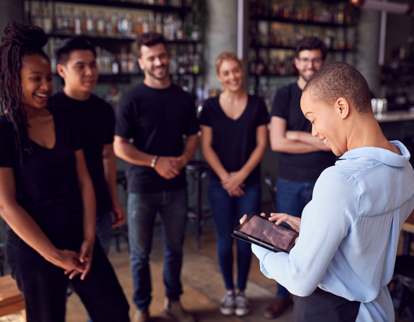 A bar manager talking to her team with a smile