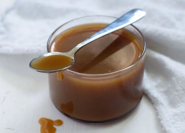Jar of butterscotch sauce with dripping spoon 