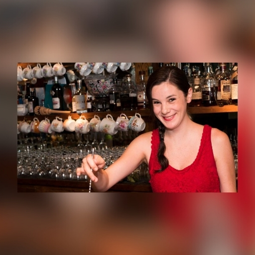 Bartender Jillian Vose from Dead Rabbit in NYC smiling at the camera and mixing a cocktail. 
