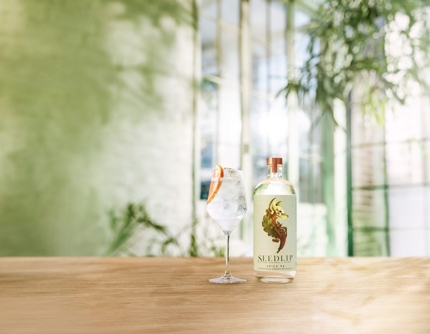 Botella de Seedlip junto a vaso servido con hielo y decorado con rodaja de naranja