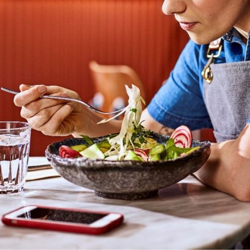   Una mujer comiéndose una ensalada, tomándose un descanso tras un turno largo  