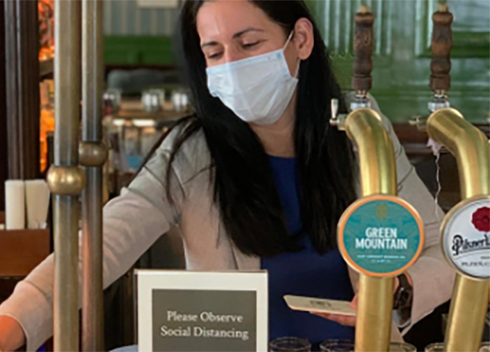 Bartender with mask serving a customer