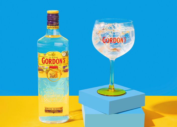 Botella de ginebra Gordon’s junto a dos copas de gin-tonic