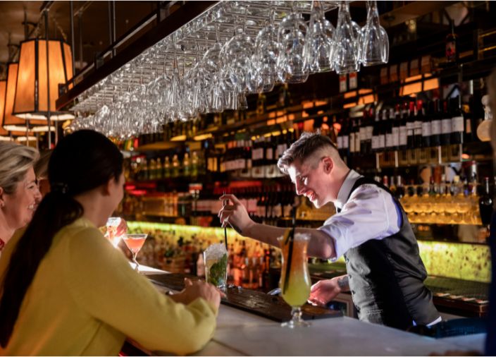 Barkeeper fügt den letzten Schliff zu einem Cocktail vor den Gästen hinzu