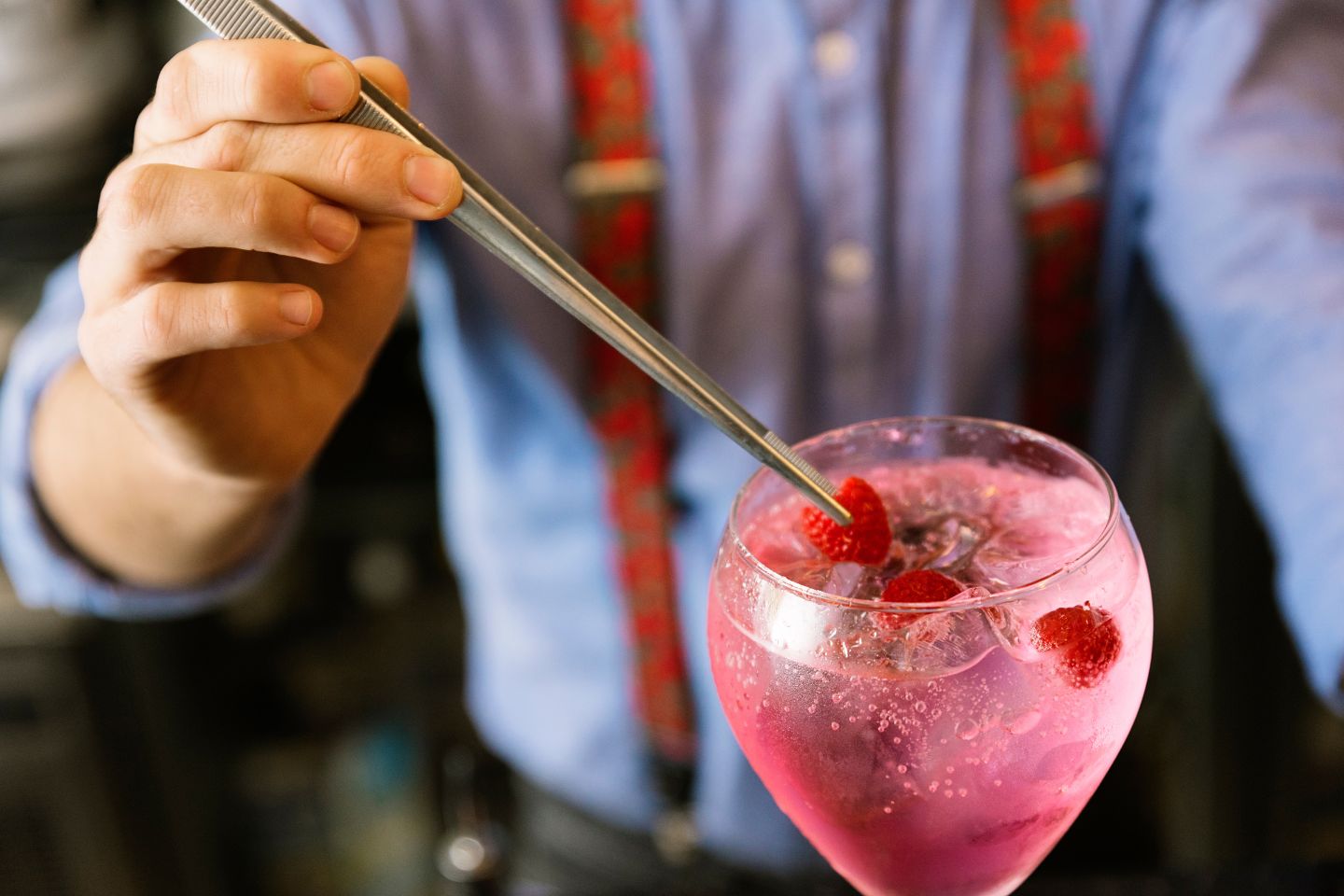 Garnish being placed on the top of a pink cocktail.