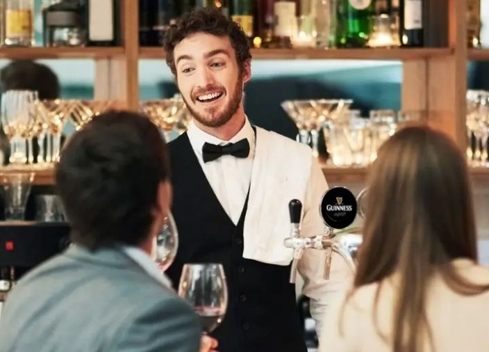 Bartender behind the bar chatting to two customers