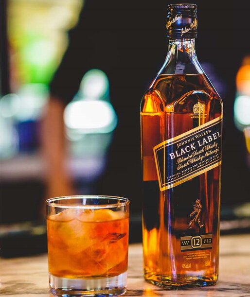 Garrafa de Johnnie Walker Black Label ao lado de um copo de whisky