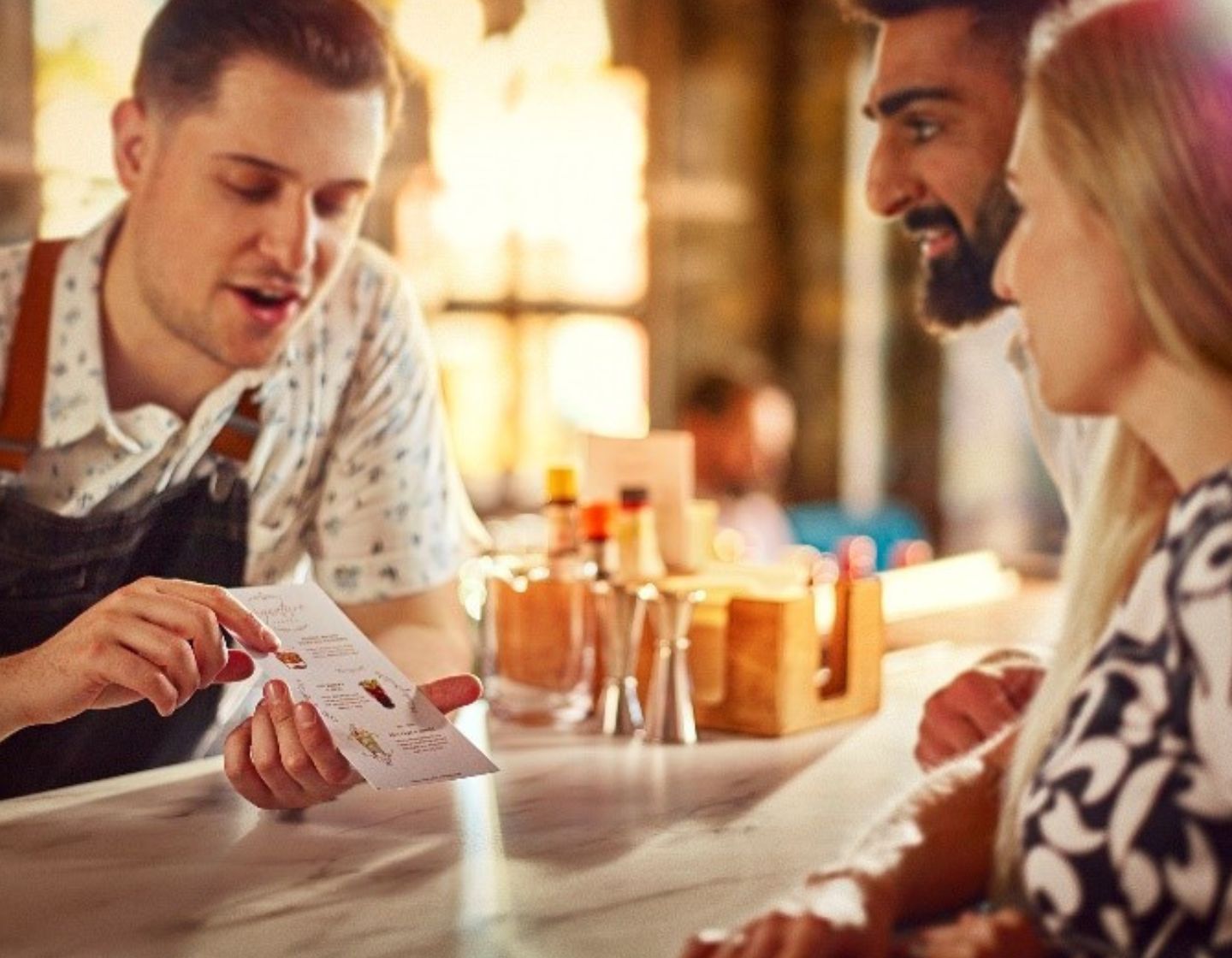 Bartender behind bar showing guests the drinks menu