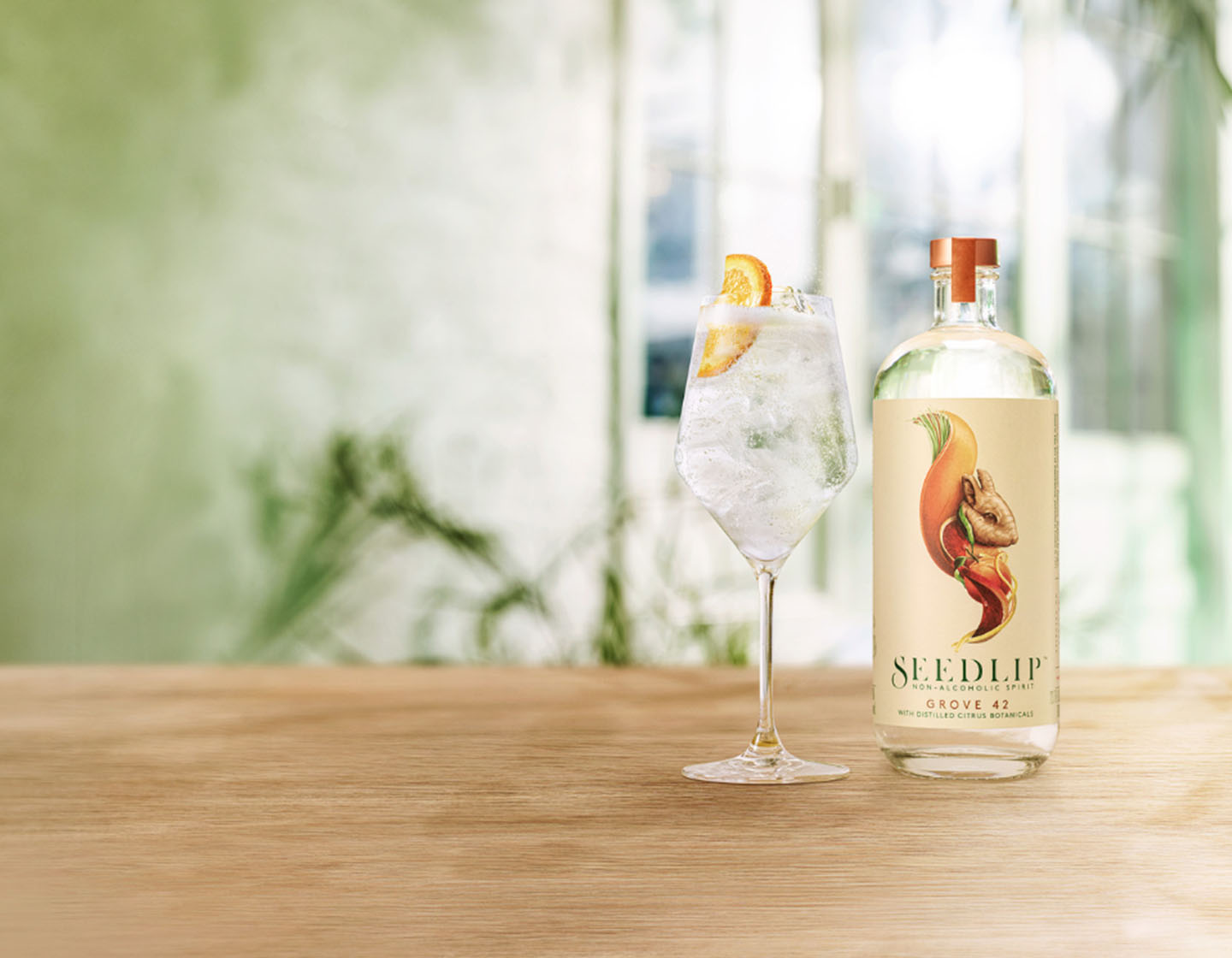 Botella de Seedlip Grove 42 en la mesa junto al cóctel