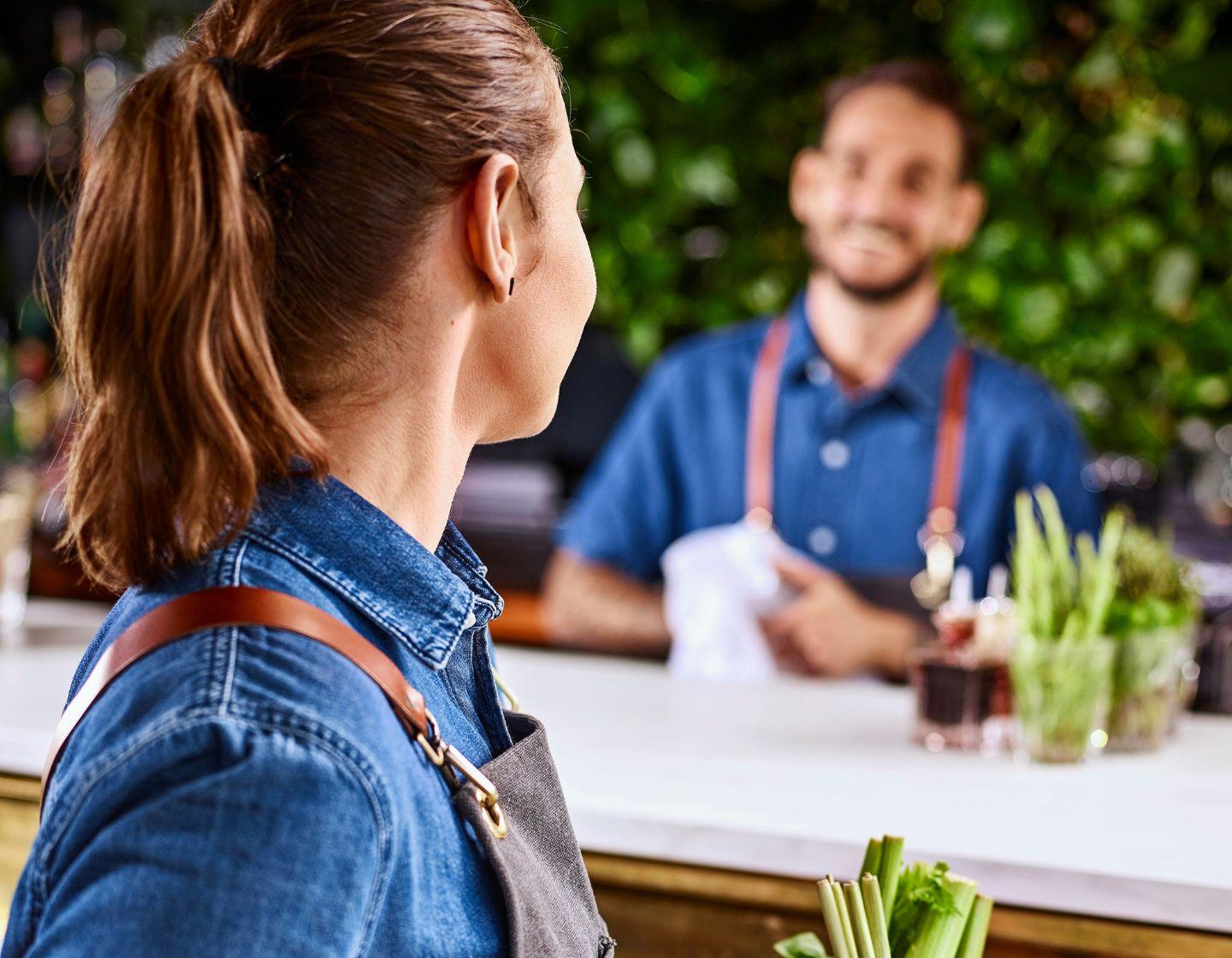 Two bartenders speak over the counter