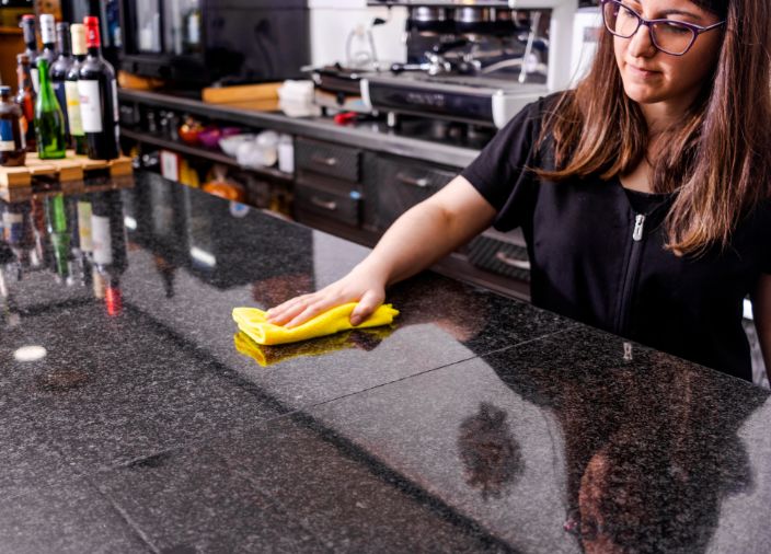 Bar staff cleaning work surface with a cloth