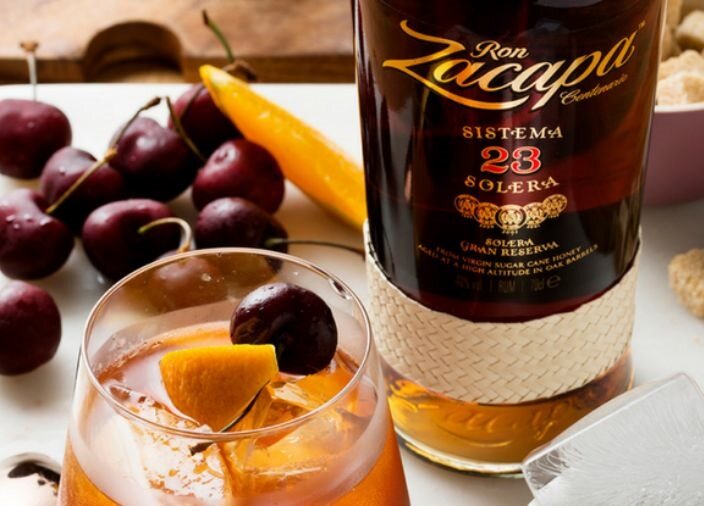 Zacapa Rum next to a glass of rum and fruit.