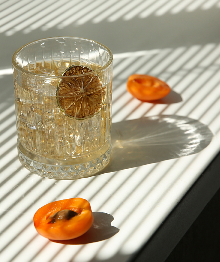 Tumbler glass with a detox drink and orange garnish.