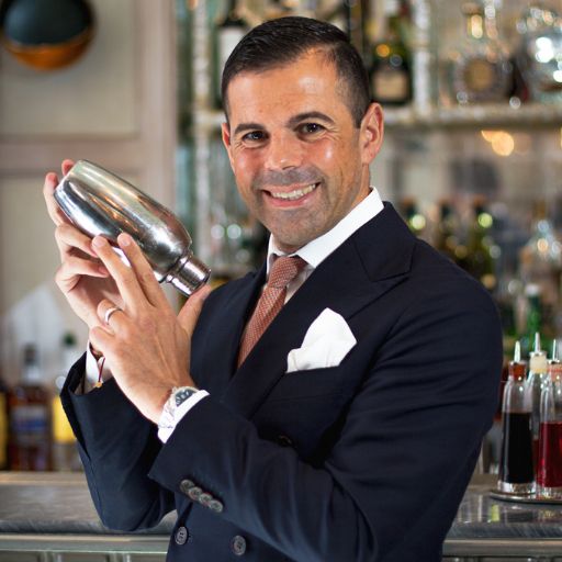 Image of Ago Perrone in a suit holding a cocktail shaker. 