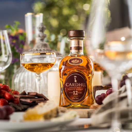 botella de cardhu rodeada por fruta y copas