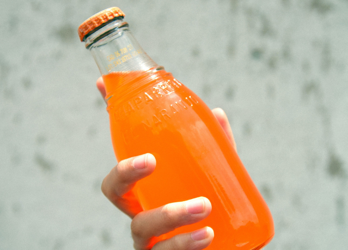 Hand holding glass bottle of soda 