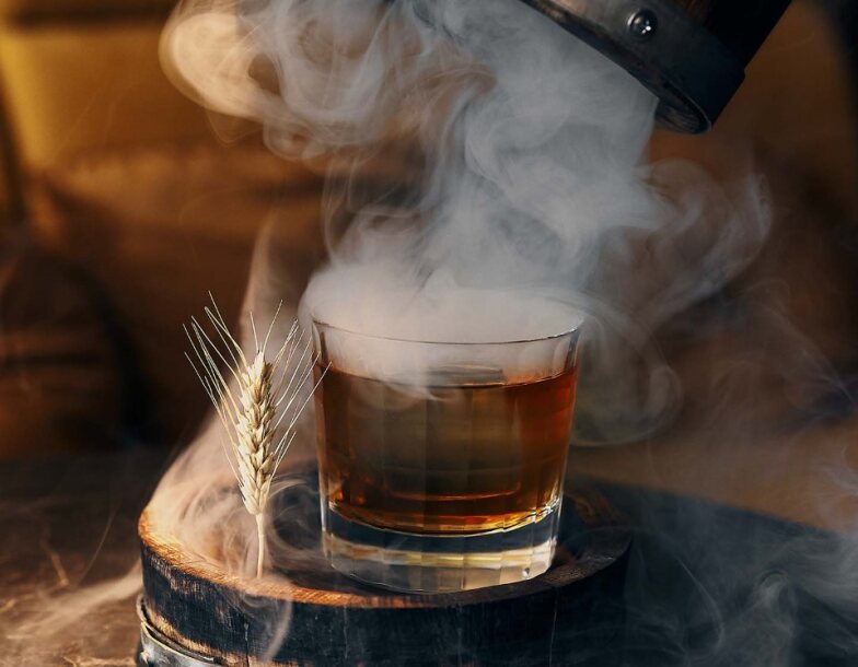 Un vaso transparente lleno de líquido rodeado de humo.