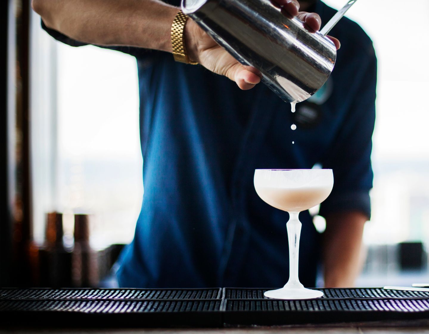 Barkeeper schüttet Cocktail in Glas