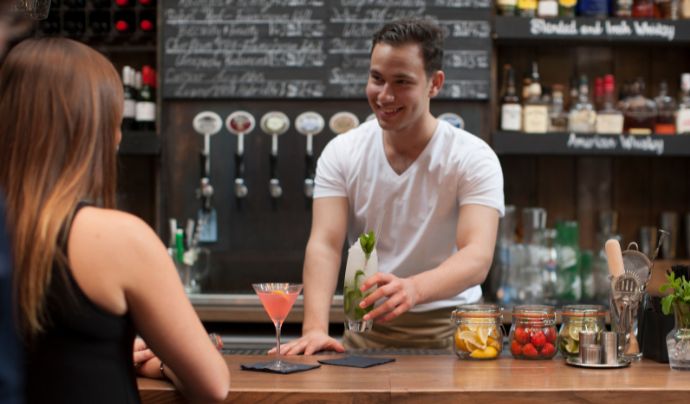 Bar staff serving a drink to a customer 