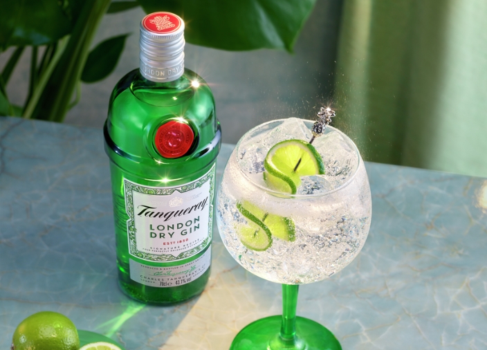 Botella de Tanqueray London Dry Gin junto a un cóctel de gin tonic con garnish de lima