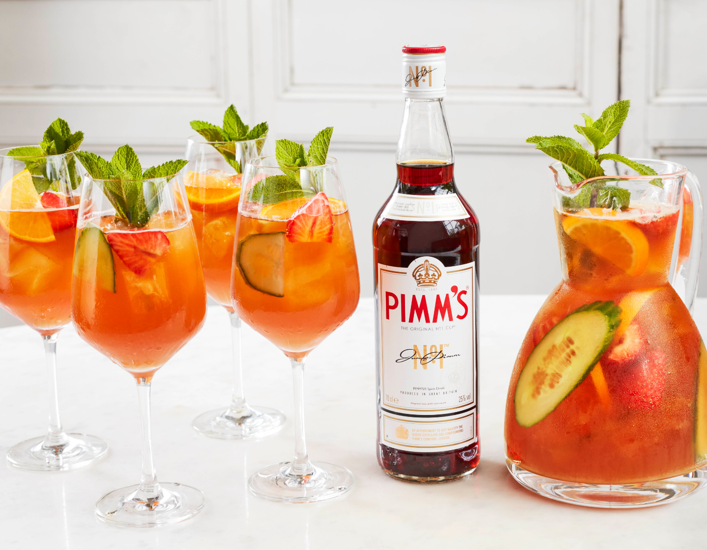 Botella de Pimm's junto a cuatro copas de cóctel y una jarra.