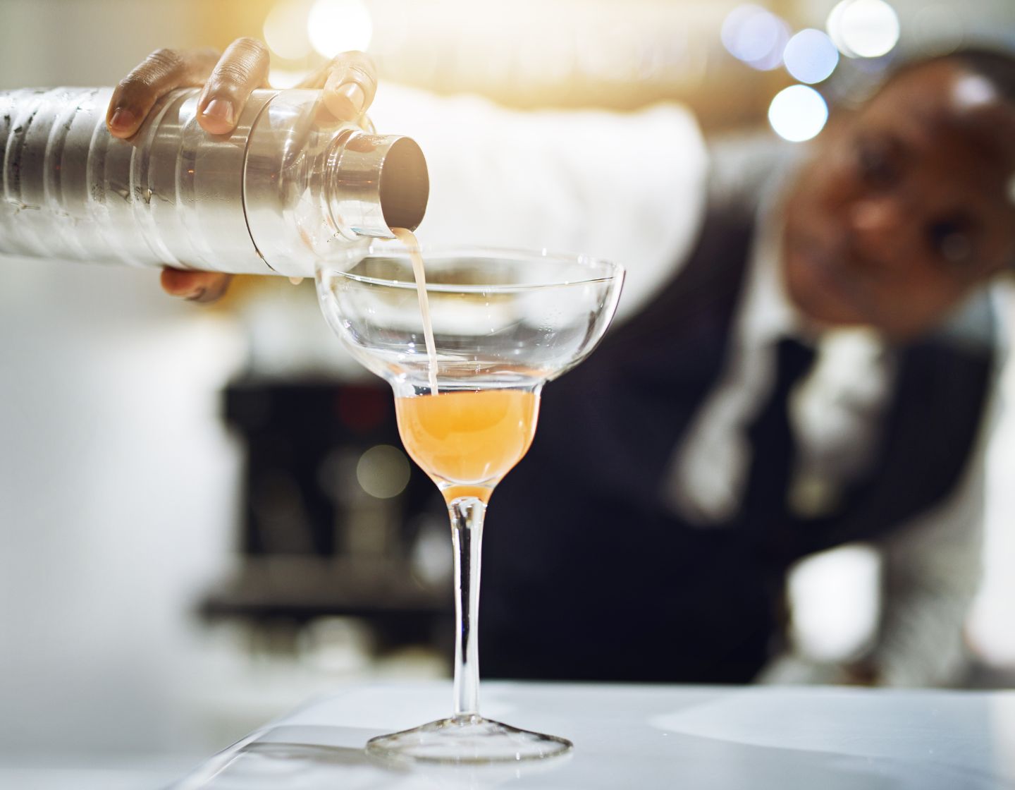 Barkeeper gießt aus einem Shaker einen klassischen Tequila-Margarita-Cocktail ein