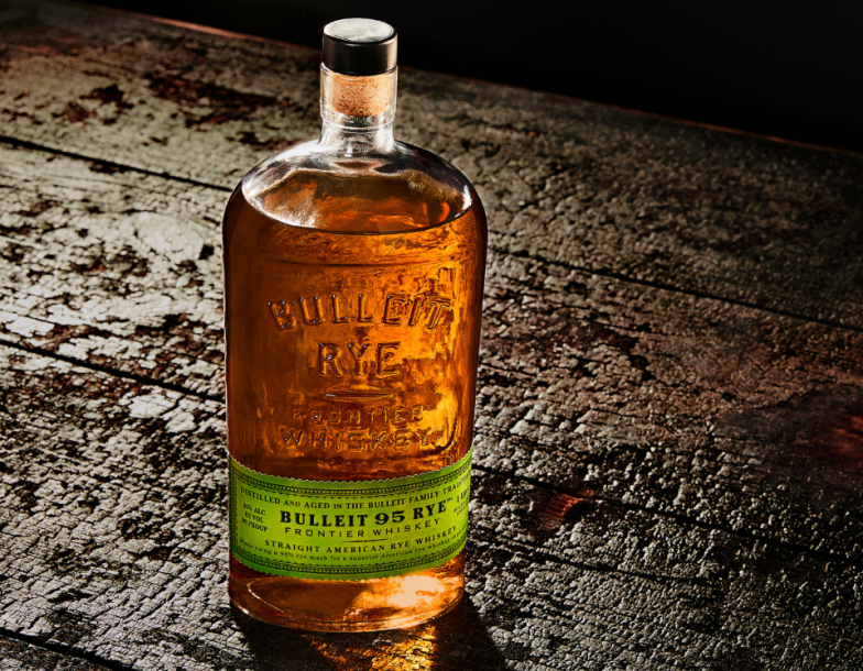 Botella de Bulleit Rye apoyada en una superficie de madera