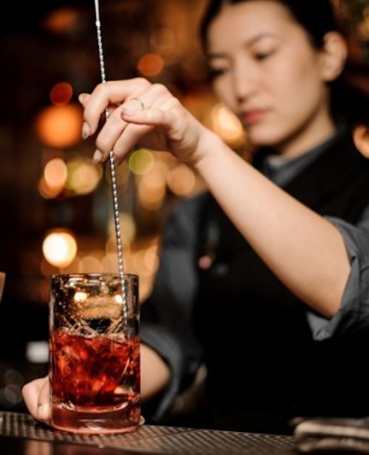 Eine Barkeeperin mixt einen roten Drink