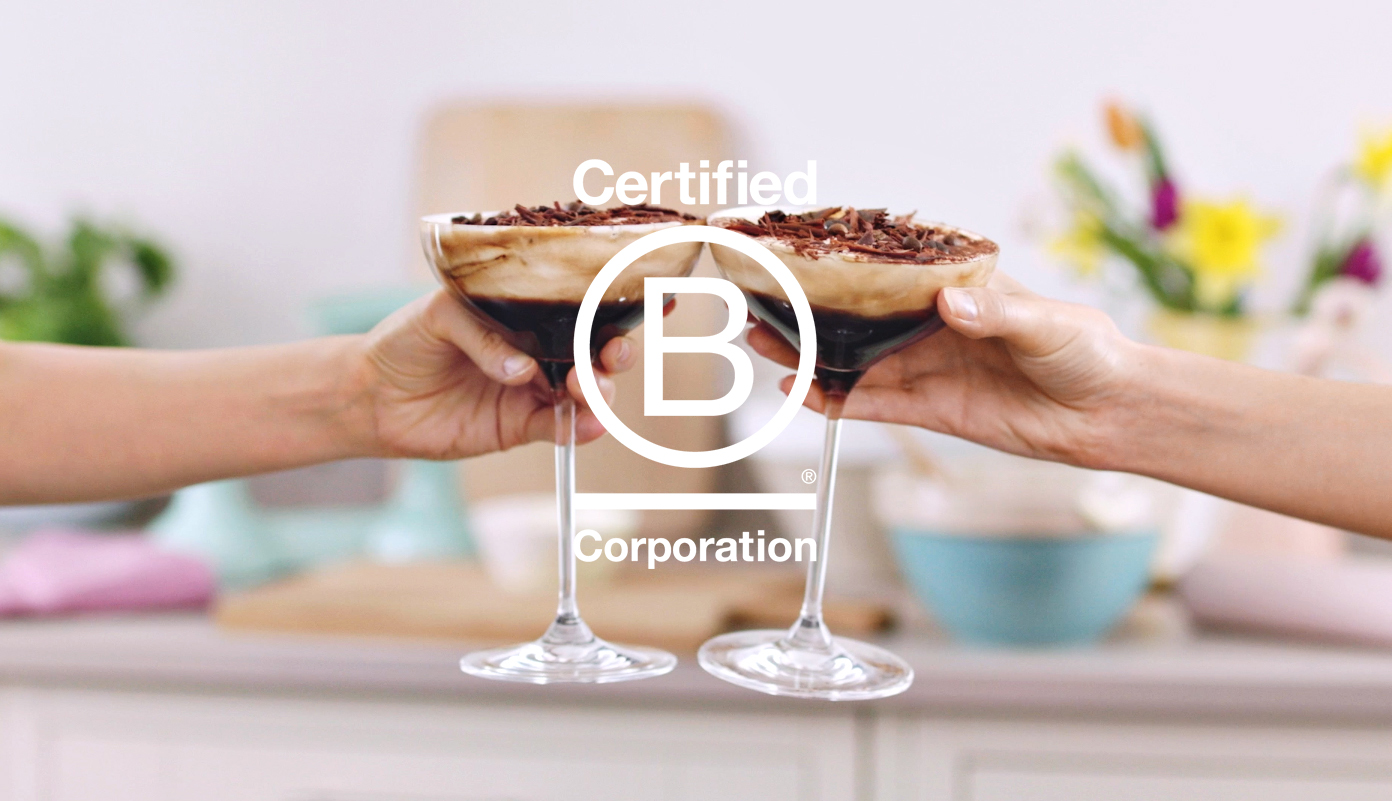 Dos personas 'brindando' con copas de martini con el logotipo de B Corp superpuesto