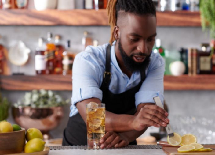  Bartender lifting lemon with tongs to garnish a drink 