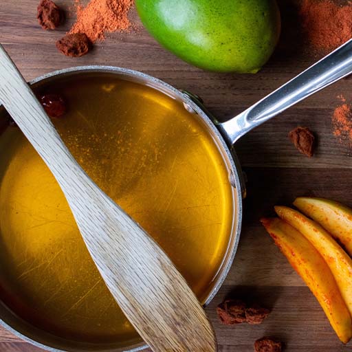 Una cacerola con almíbar rodeada de especias y mango.