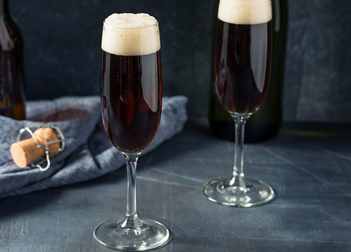 Two Black Velvet cocktails in sparkling wine flutes. 