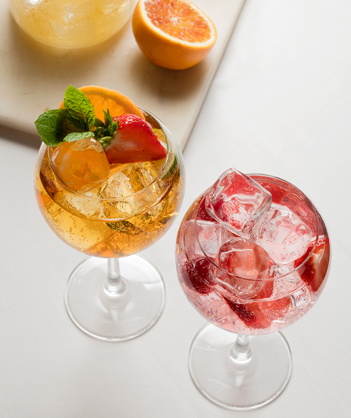 Two cocktails in wine glasses with garnish