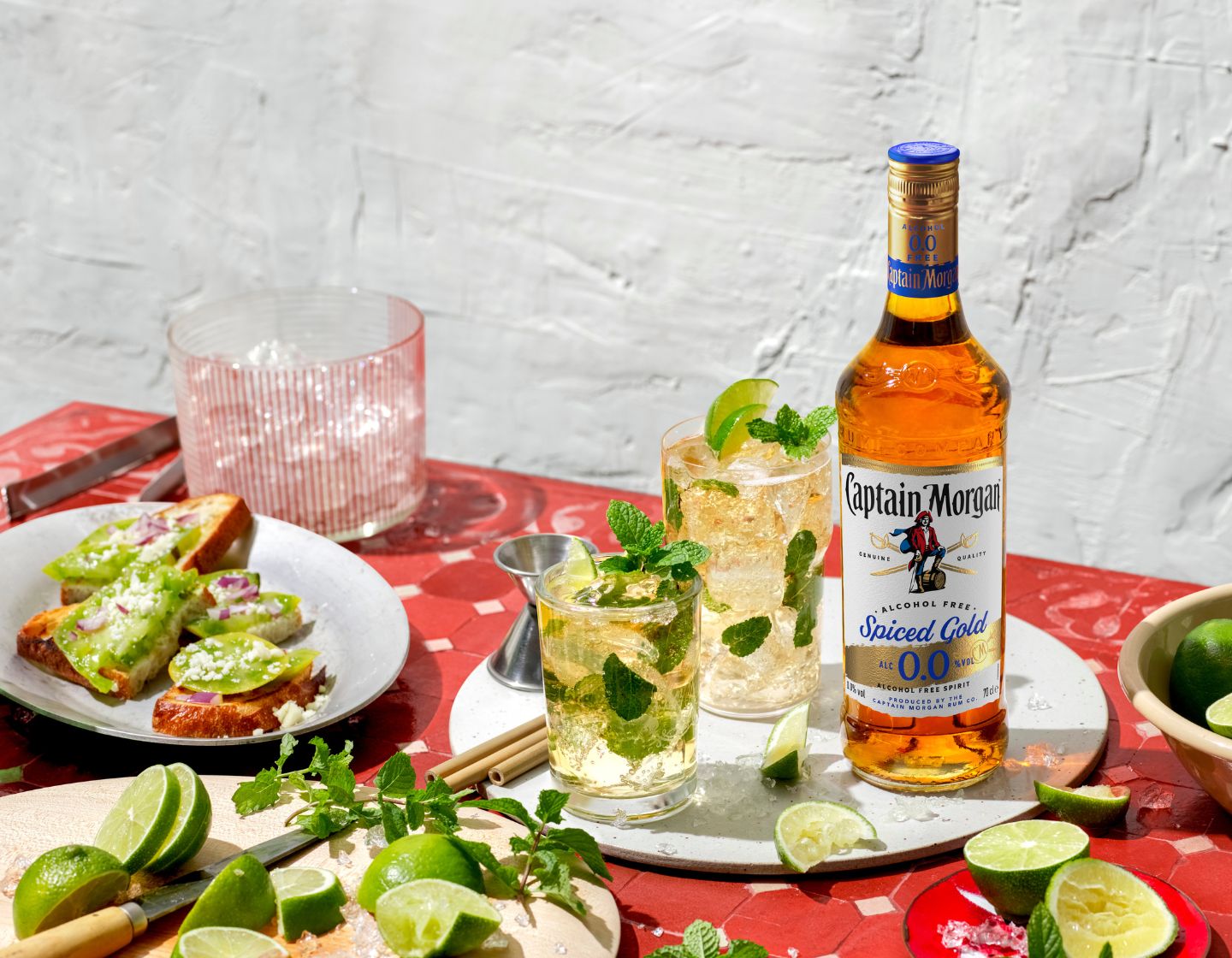 Eine Flasche Captain Morgan Spiced Gold 0.0% alkoholfrei steht auf einem Tisch umgeben von Getränken und Essen