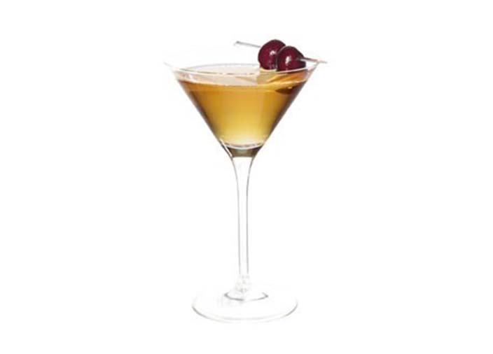 A Manhattan cocktail in a Martini glass against a white background.