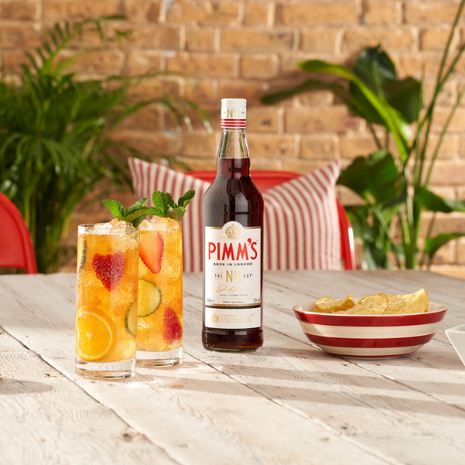 2 cocteles junto a una botella de pimm's sobre una mesa de madera