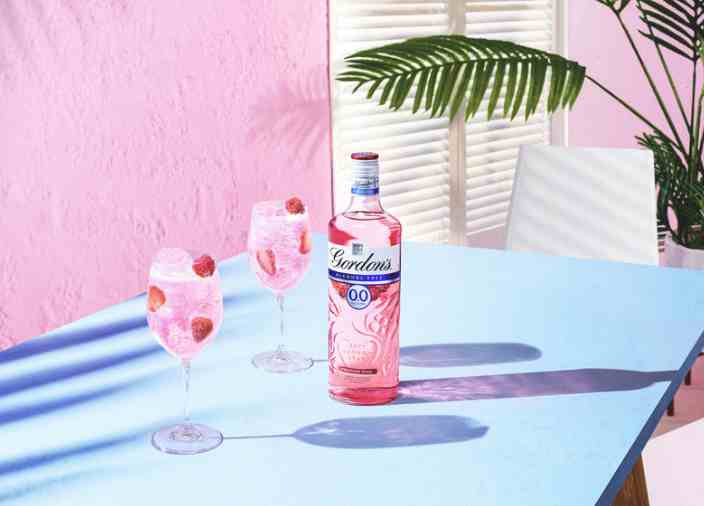 Two Gordon’s Pink 0.0% Pink gin cocktails on a summery table.