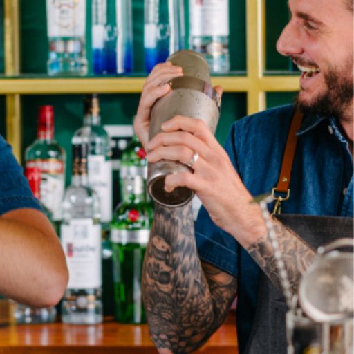 Two bartenders working behind the bar shaking cocktails together