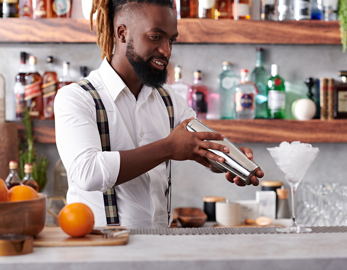 Male bartender shaking a cocktail shaker with both hands. 