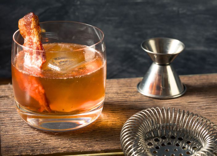 Cóctel Old Fashioned con garnish de tocino de arce.