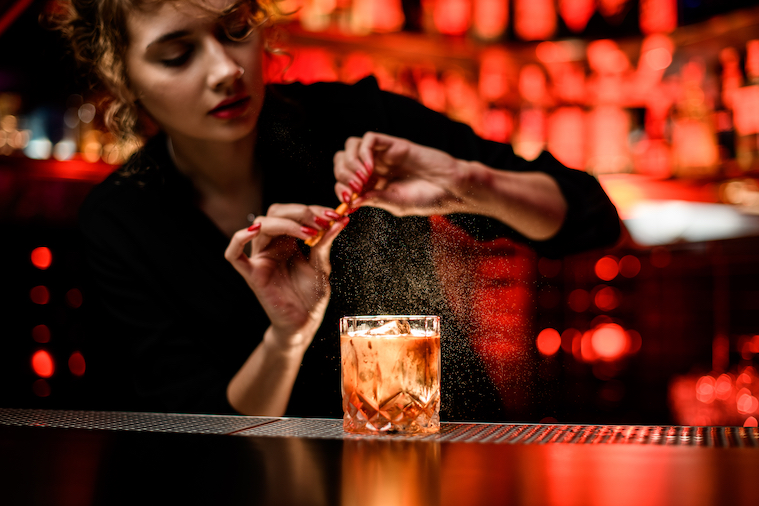 Bartender mulher borrifando um drinque