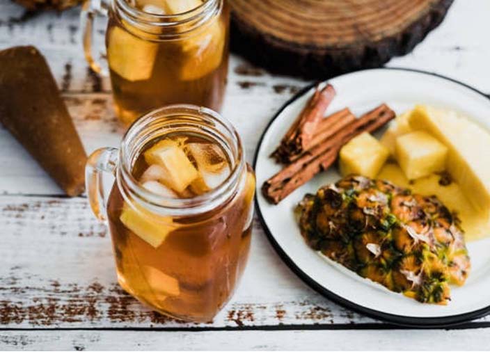 Two glass jars filled with drinks beside a plate of ingredients.